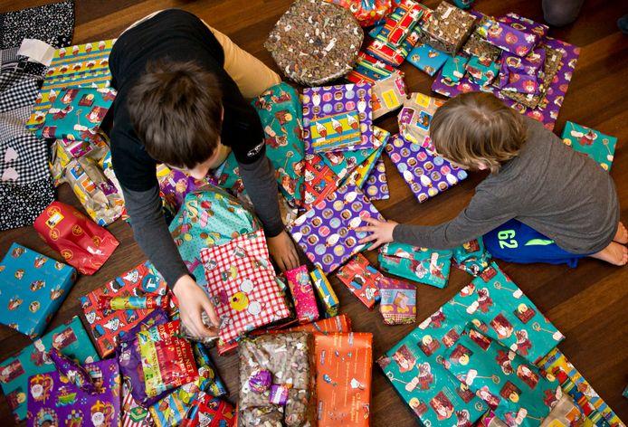 een grond vol met cadeautjes en 2 kinderen die de cadeautjes uitpakken